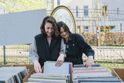 Smiling lesbian couple selecting records at market stall