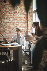 Female colleagues having coffee while using laptop startup company