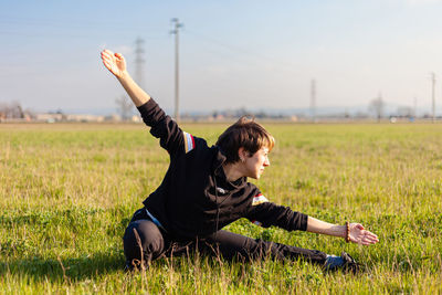 Caucasian young woman practicing wushu martial art in a green meadow