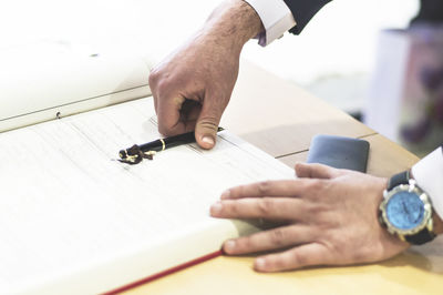 Cropped hands of man on book at table