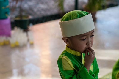 Close-up of boy with fingers in mouth wearing traditional clothing