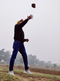 Rear view of man standing on field against sky