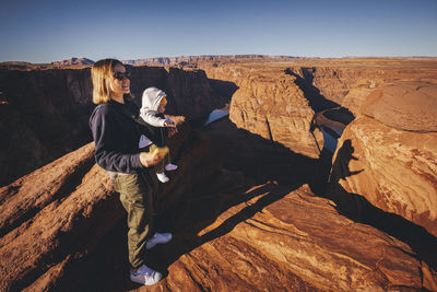 A woman with a child is standing near horseshoe bend, arizona