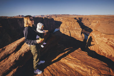 A woman with a child is standing near horseshoe bend, arizona