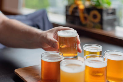 Midsection of woman holding beer glass on table