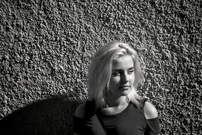 Close-up of young woman looking away against wall