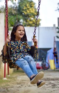 Happy girl playing on swing at playground