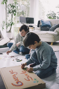 Mother and son drawing in living room at home