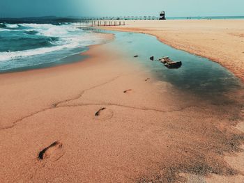 Scenic view of beach against sky with footprints