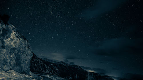 Low angle view of snowcapped mountain against sky at night