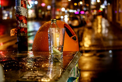 Bottle and drinking glass on table at night