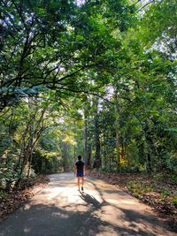 Rear view of man walking on road in forest