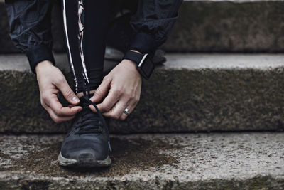 Low section of young woman tying shoelace on steps