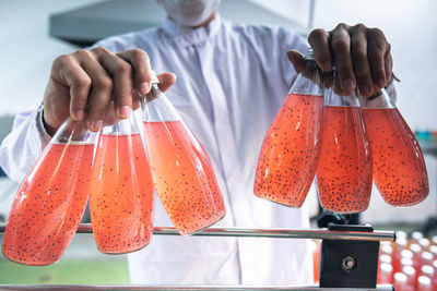 Staff putting bottles of herbal drinks, which contain basil seed, on the conveyor belt, 