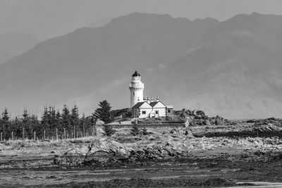 Lighthouse by building against sky