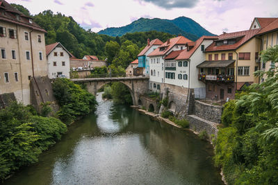 Stone capuchin bridge and historic houses reflected in the selca sora river in skofja loka slovenia