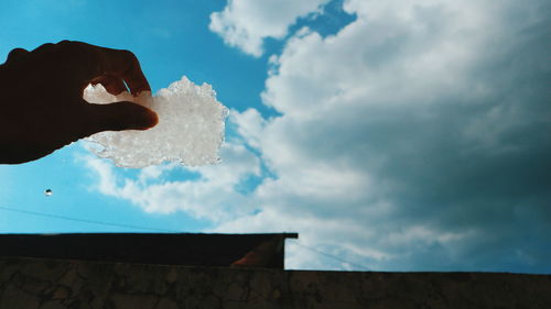 Low angle view of hand against blue sky