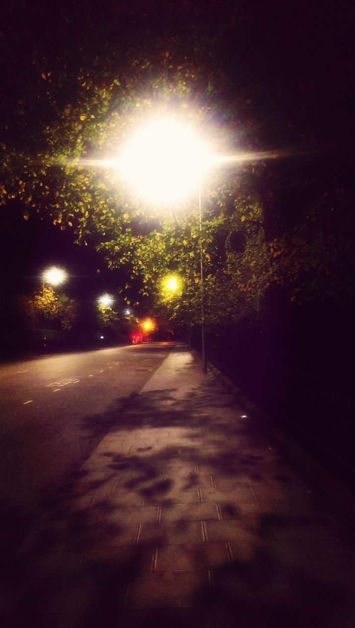 illuminated, night, the way forward, street light, street, road, transportation, lighting equipment, diminishing perspective, tree, lens flare, road marking, vanishing point, glowing, no people, empty, empty road, dark, sky, car