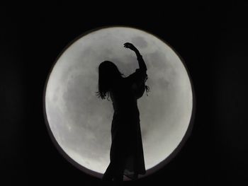 Silhouette woman standing against moon at night