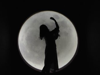 Digital composite image of silhouette woman standing against moon