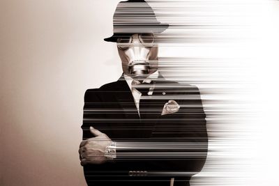 Digital composite image of businessman wearing gas mask against wall