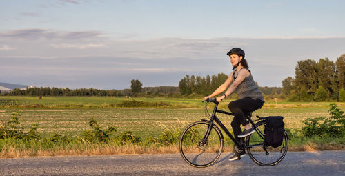 Side view of young woman riding bicycle on field