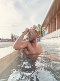 Shirtless boy in swimming pool against sky. posing in sirmione thermal pool close to the garda lake