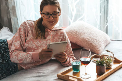 Young woman using smart phone while sitting on laptop