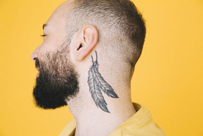Close-up of neck tattoo on man against colored background