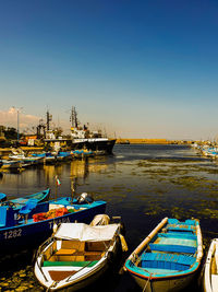 Boats moored in harbor at sunset