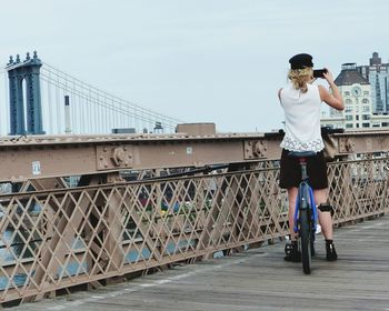 Full length rear view of woman standing on bridge