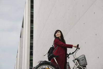 Businesswoman taking bicycle in the background of modern building