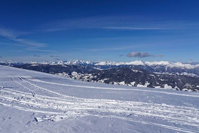 Snow covered landscape against blue sky