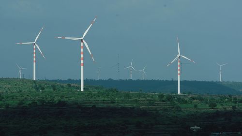 Windmills on field against sky