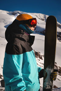 Close up portrait of a guy holding skis in winter, sportswear, winter holidays in nature, traveling