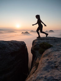  young brave girl with an athletic figure jumping between rock cliffs. euphoria of personal victory