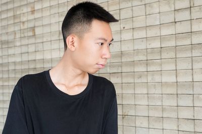 Close-up of young man looking away against wall