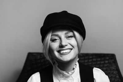 Portrait of smiling young woman against wall