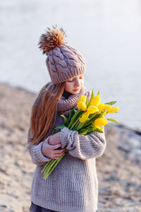 Cute girl holding tulip flower standing at lakeshore