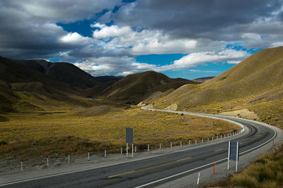 Scenic view of road by mountains against sky