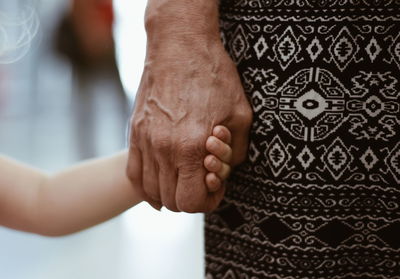 Midsection of woman holding hand child hand