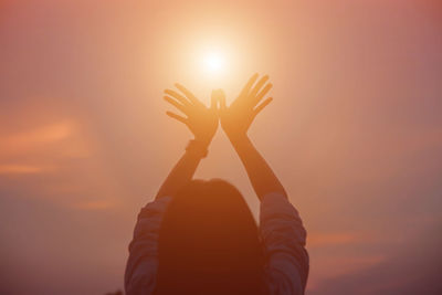 Silhouette hand against orange sky during sunset