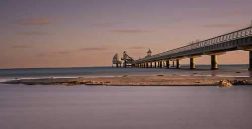 Pier over sea against sky during sunset