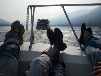 Low section of people sitting by sea