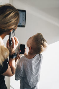 Siblings using digital tablet mounted on wall at home