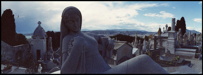 Statue in city against sky