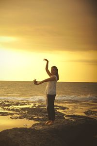 Full length of woman standing on beach during sunset