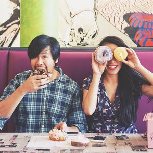 Portrait of man eating donut with woman at restaurant