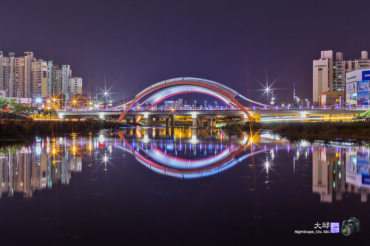 illuminated, night, architecture, built structure, city, water, building exterior, river, connection, bridge - man made structure, reflection, waterfront, transportation, clear sky, famous place, travel destinations, cityscape, capital cities, city life, modern