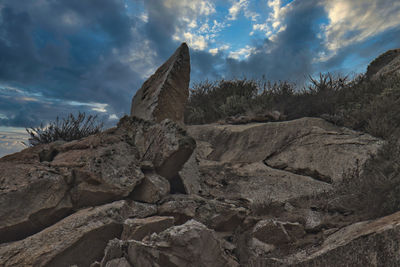 Low angle view of rocks on rock against sky